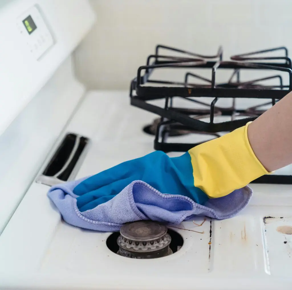 image of a professional cleaner scrubbing a stove top